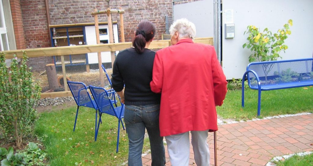 Pflegekraft stützt Seniorin