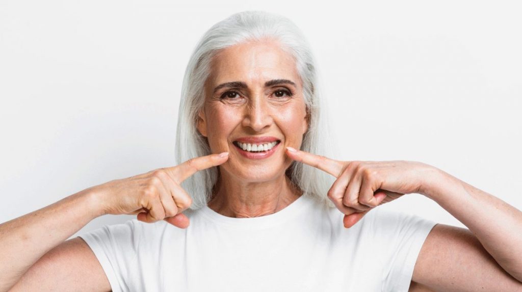 Seniorin zeigt Ihre gesunden Zähne